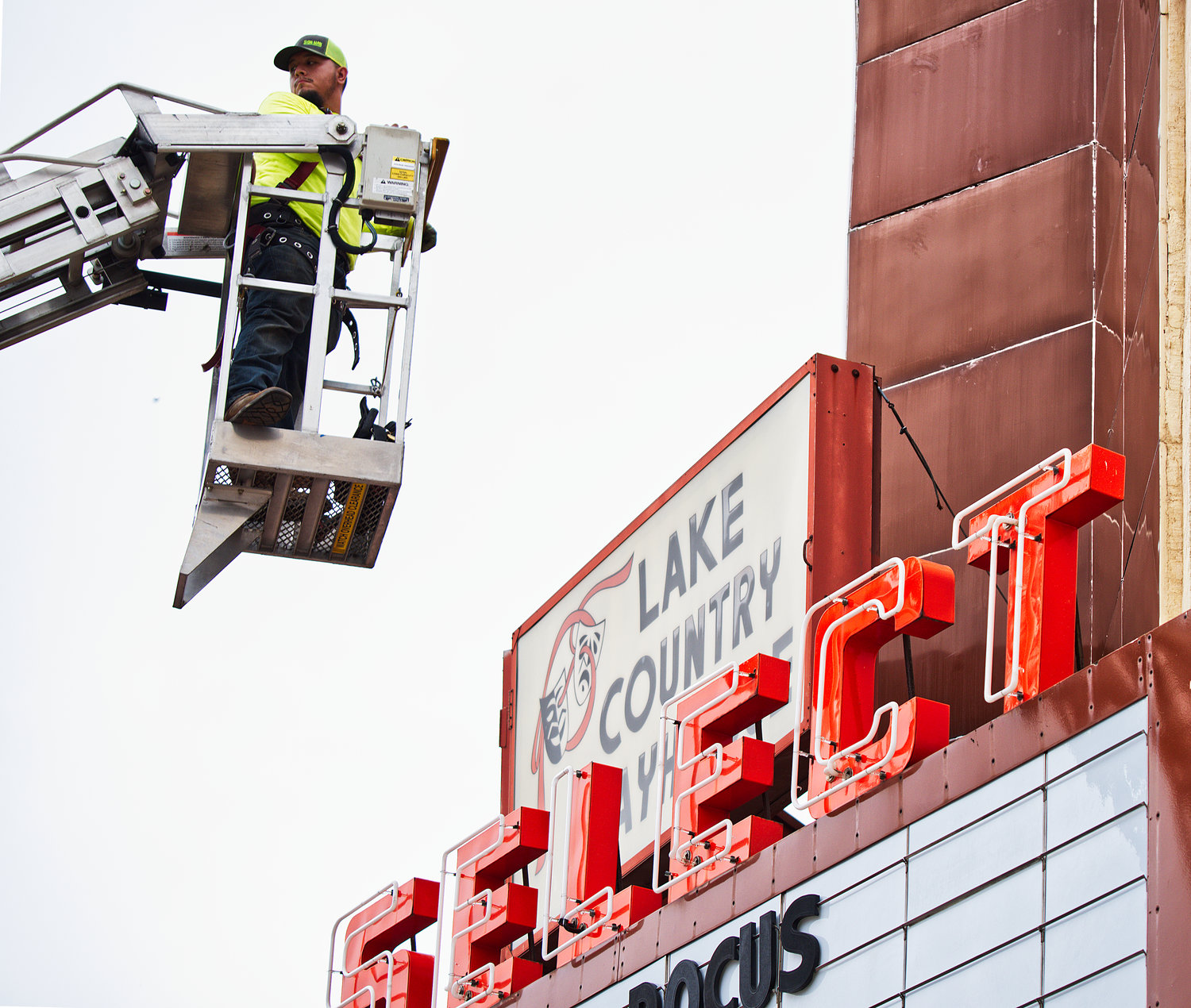 Xaciel Devora works on the neon lights atop the marquee at the Select Theater.